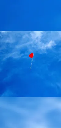 This live phone wallpaper features a charming red balloon, floating peacefully across a backdrop of clear blue skies