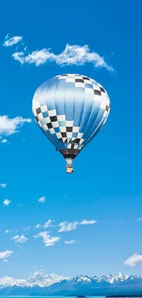 This stunning phone live wallpaper depicts a hot air balloon flying over a serene body of water