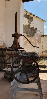 This phone live wallpaper showcases an antique olive oil machine inside an old village building