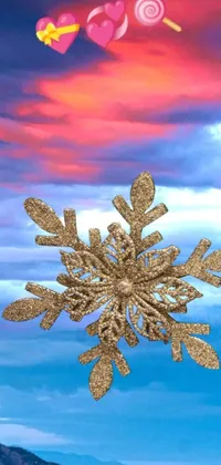 This phone live wallpaper showcases a serene snowflake resting atop a snowy landscape, accompanied by a colorful sky featuring golden clouds