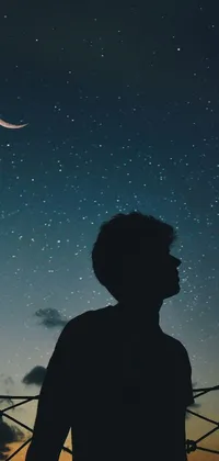 This stunning phone live wallpaper depicts a mysterious person standing in front of a fence at night