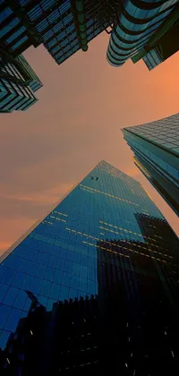 This phone live wallpaper features a group of glass-walled skyscrapers reflected in the orange glow of the sunset