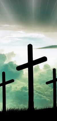 The live phone wallpaper portrays a serene scene of three crosses silhouetted against a cloudy sky, evoking religious reverence and spirituality
