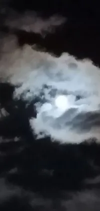 This smartphone wallpaper offers a captivating view of a full moon as it shines through the clouds, creating a sense of a watchful presence in the night sky