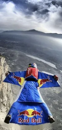 This dynamic mobile live wallpaper showcases an exhilarating image of a person in a red bull suit flying through the air atop a cliff