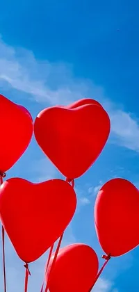 This live wallpaper showcases a group of heart-shaped balloons in deep crimson hue, rising up against a tranquil blue sky