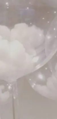 This live wallpaper features clear balloons on a table with dreamy clouds in the background