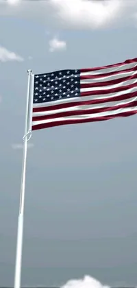This phone live wallpaper showcases a realistic digital rendering of the American flag flying in the wind on a cloudy day
