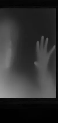 This phone live wallpaper showcases a black and white photo of two hands reaching out of a window