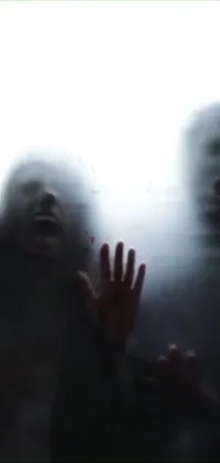 This phone live wallpaper shows a group of people with zombie-like faces standing in front of a misty window
