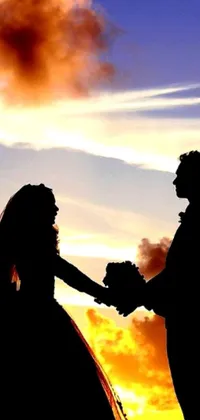 Looking for a stunning live wallpaper for your phone? Check out this gorgeous silhouette of a bride and groom holding hands against a sunset backdrop