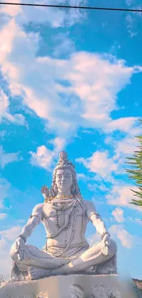 This live wallpaper depicts an intricately detailed statue of a man meditating atop a rock; a portrayal of the Hindu god, Shiva