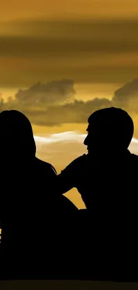 This live phone wallpaper features a romantic silhouette of two individuals sitting closely to each other, set against a dusky and dramatic background