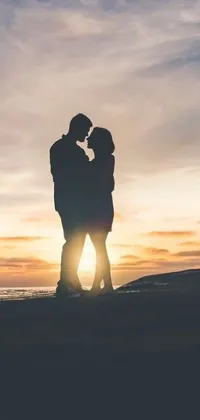 This delightful live wallpaper for your phone features a very romantic image of a couple embracing and kissing passionately on a sandy beach, as the stunning sunset creates a warm and inviting atmosphere