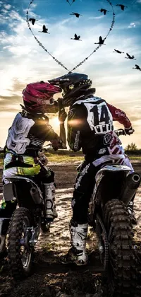 Rev up your phone's home screen with the thrilling action of this live wallpaper! Featuring two dirt bikes sitting side by side, this image captures a dramatic moment of celebration in which the riders share a passionate kiss
