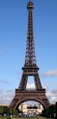 Bring the stunning beauty of the Eiffel Tower to life on your phone with this breathtaking live wallpaper! Featuring a captivating scene with a group of people standing before the mesmerizing monument, this wallpaper is perfect for those who love to travel or appreciate magnificent architecture