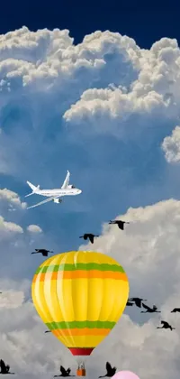 Experience an enchanting wallpaper with vibrant and exotic visuals of birds dancing around a hot air balloon hanging amidst layers of bright yellow clouds