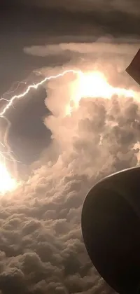 This phone live wallpaper showcases a stunning image of a commercial airliner flying through a cloudy sky while lightning bolts flash in the background
