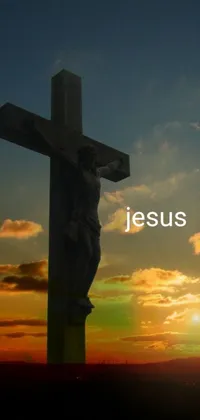 This phone live wallpaper features a beautiful cross on a hill with a sunset in the background