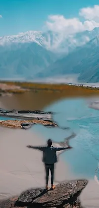 This live wallpaper features a stunning view of a person standing on a rock next to a river in the Himalayas