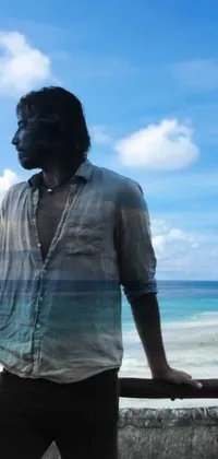 This phone live wallpaper showcases a man standing on a beach next to the ocean with the beautiful Maldives in the background