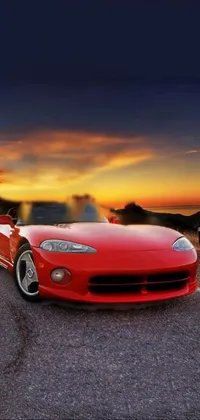 This dynamic phone live wallpaper showcases a bright red sports car parked on the side of a scenic highway, while a venomous cobra slinks across the road in the foreground