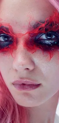 This phone live wallpaper features a person with bright pink hair and fiery red watery eyes against a background of Lady Gaga as Harley Quinn