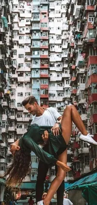 This is a stunning phone live wallpaper featuring a beautifully painted man and woman dancing in front of a tall city building in the style of Kowloon Walled City