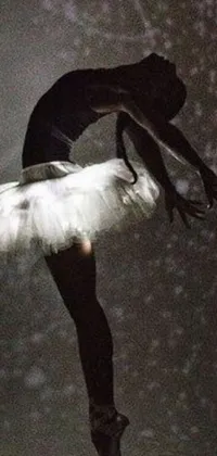 This phone live wallpaper features a striking black and white photograph of a ballerina performing an elegant arabesque pose in a tutu