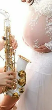 This stunning and highly detailed live phone wallpaper features a woman in a flowing white dress playing a saxophone with her visible pregnancy belly