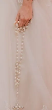 This phone live wallpaper features a stunning image of a bride holding a delicate rosary, against a beautiful background inspired by impressionism