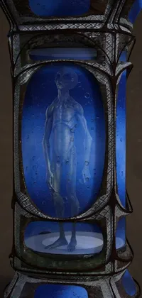 This live phone wallpaper showcases a compelling surrealist sculpture- a half human half alien reliquary surrounded by a blue glass vase on a table