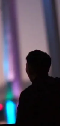 This phone live wallpaper captures a captivating scene of a man standing in front of a bridge at night, immersed in the excitement of a live concert