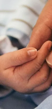 This live wallpaper is a heartwarming composition of a close-up shot of a hand holding a baby's tiny hand