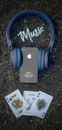 This phone live wallpaper showcases a pair of headphones resting on top of a colorful pile of cards, graffiti, and the classic Apple logo