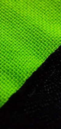 This phone live wallpaper features a close-up of a green and black cloth with subtle movements and shadows, inspired by video game textures and a high visibility (hivis) style