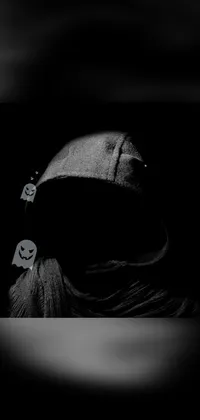 This phone live wallpaper features a black and white photo of a hooded figure wearing a dark visor, perfect for a Halloween-themed background