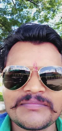 This unique phone live wallpaper features a close-up image of a person wearing black sunglasses with a beautiful, scenic outside view in the blurred background