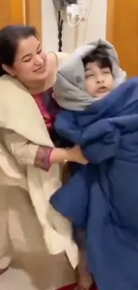 This stunning phone live wallpaper depicts a heartwarming scene of a woman cradling a bundled up child