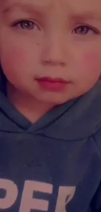 This live phone wallpaper showcases a close-up of a toddler wearing a hoodie with a cute pout