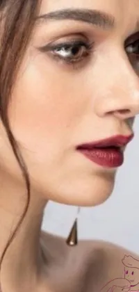 Enhance your phone screen with this stunning live wallpaper! Featuring a striking close-up of a woman with long hair, this captivating image showcases deep red lips, a silver earring, and ivory make-up