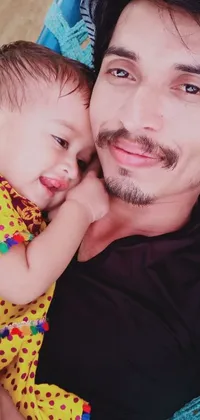 This live wallpaper captures a heartwarming moment of a man lying on top of a bed holding a baby in his arms