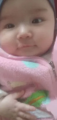 This phone live wallpaper showcases an adorable baby wearing a pink hoodie and a charming hat, all in a close-up view