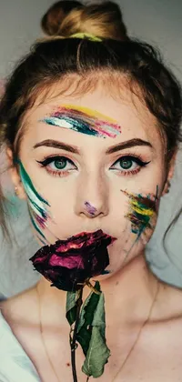 This mesmerizing live wallpaper features a colorful teenage girl with face paint holding a rose in front of her face