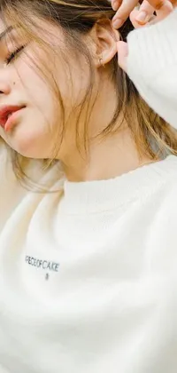 This lovely phone live wallpaper features a stunning close-up shot of a person wearing a cozy white sweater