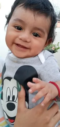This lovely phone live wallpaper features an up-close shot of a smiling adult holding an adorable baby dressed as Mickey Mouse close to their chest