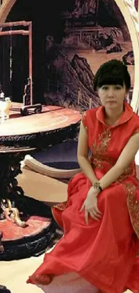 Experience the mystique of Chinese culture with this exquisite phone live wallpaper featuring a woman in a stunning red dress sitting in front of a luxurious table