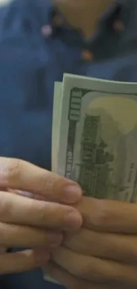 This live wallpaper features a close-up shot of a person holding a stack of money in their hands