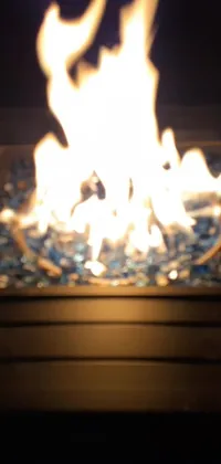 This phone live wallpaper captures the beauty of a nighttime fire, with a close-up view of flames in a glass bowl