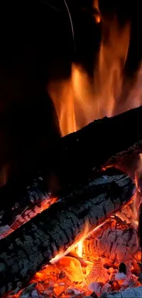 This phone live wallpaper features a high resolution, 8K image of a crackling fire in a fireplace or outdoor campfire pit